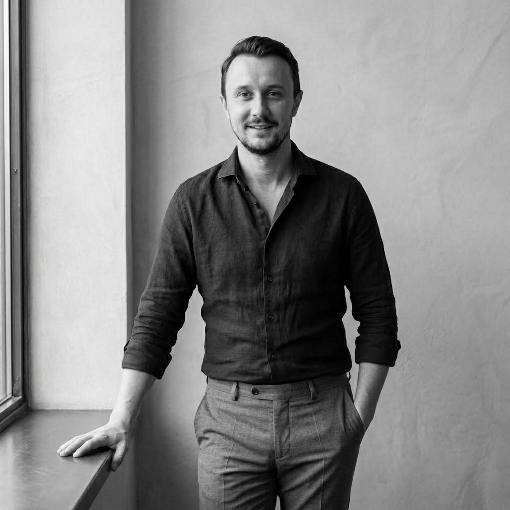 Nicholas Szymanski standing by a window, smiling towards the camera.